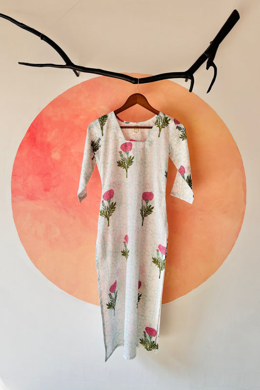Floral-patterned dress hanging on a hanger against a pink circular background