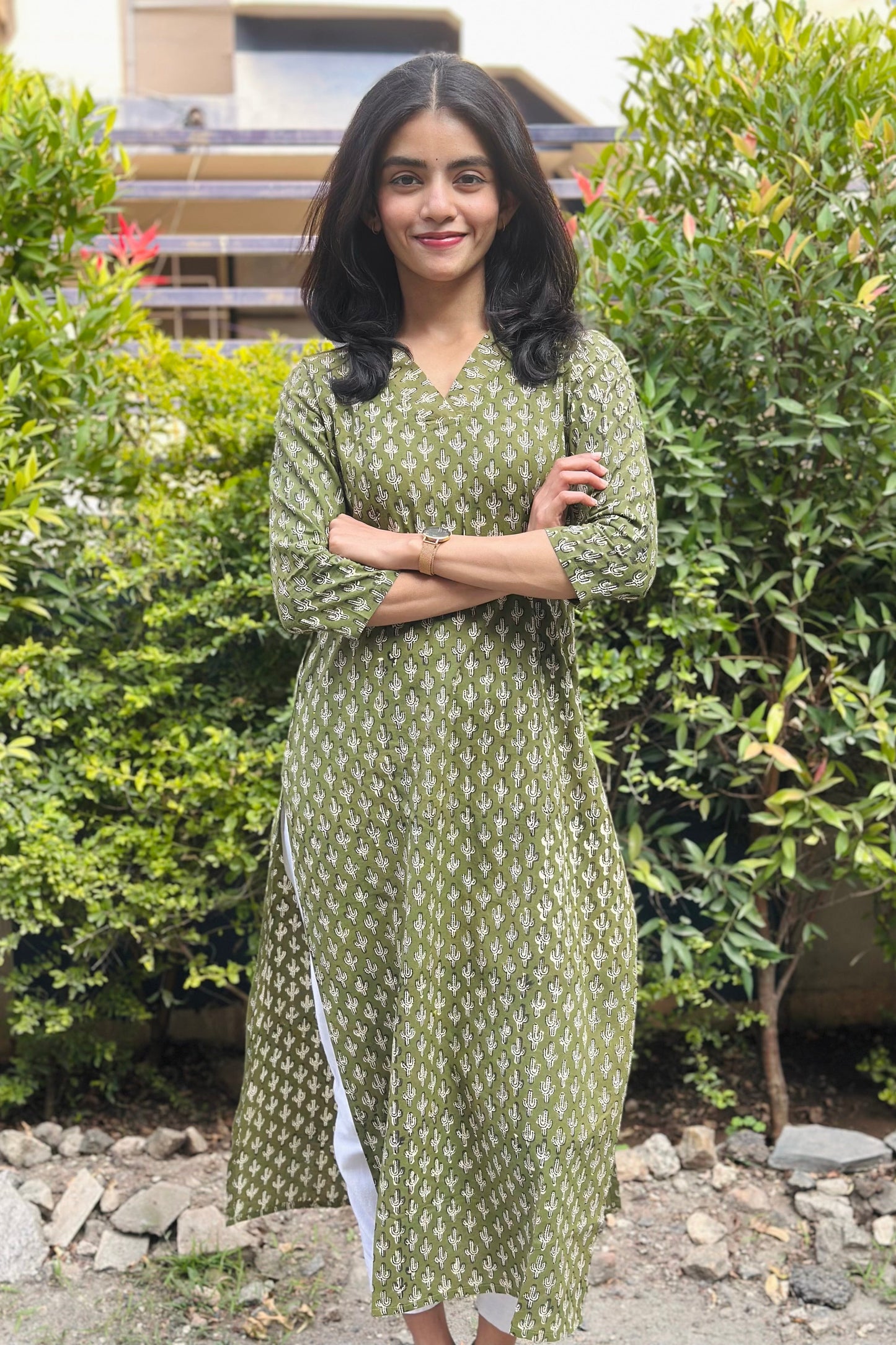 Woman in a green dress standing outdoors with greenery in the background