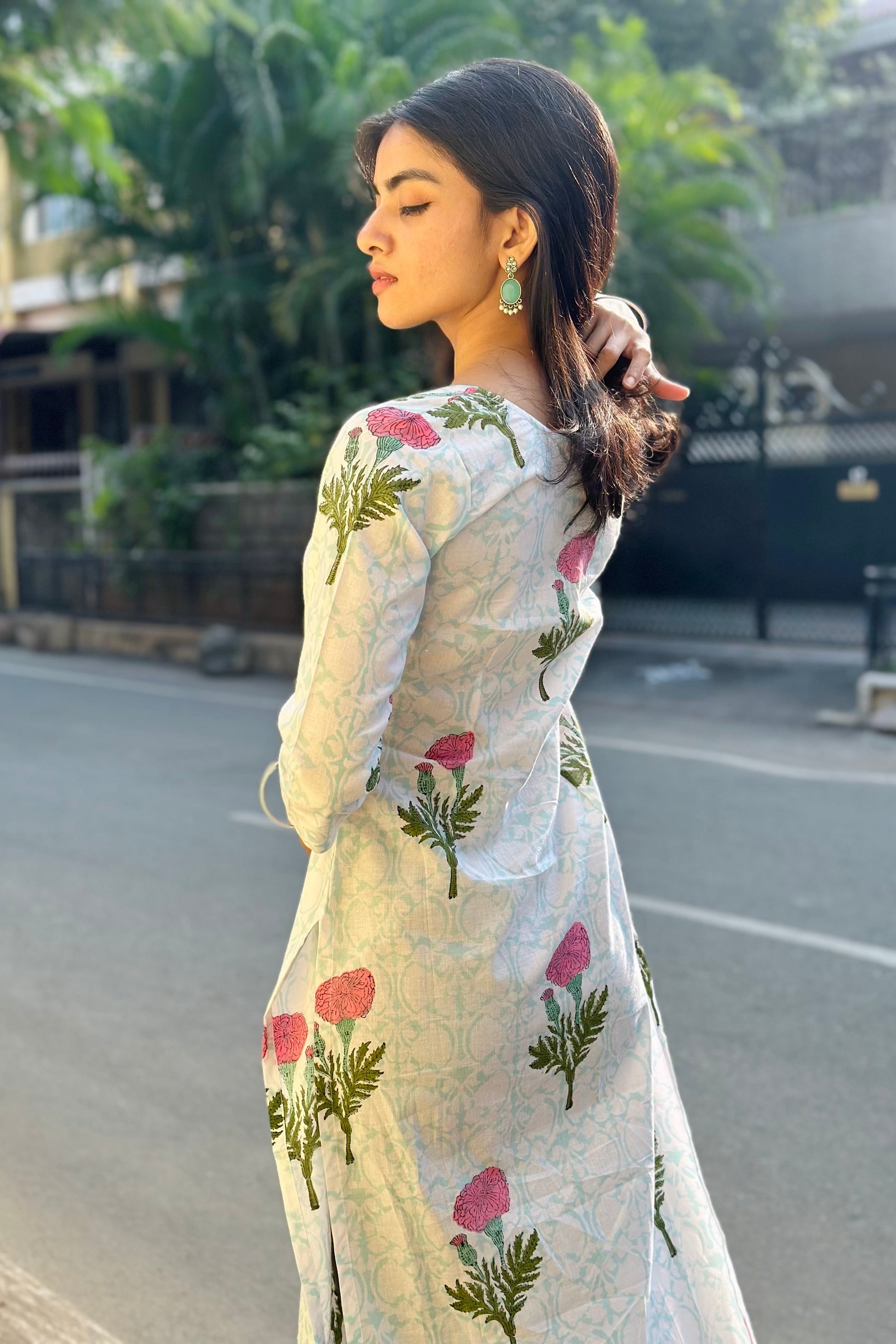 Woman in a floral kurta standing on a street with greenery in the background