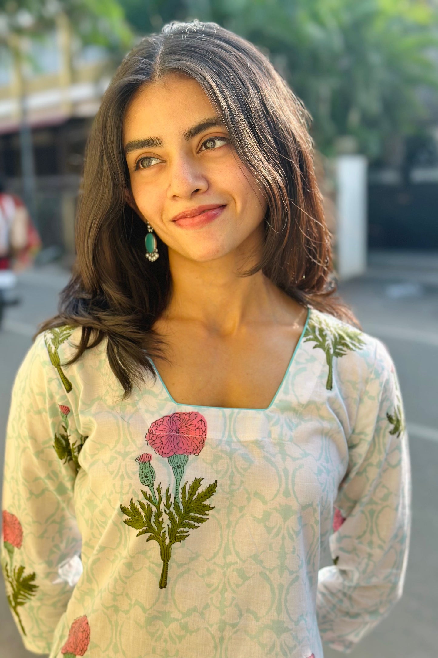 Woman wearing a floral kurta with a blurred street background